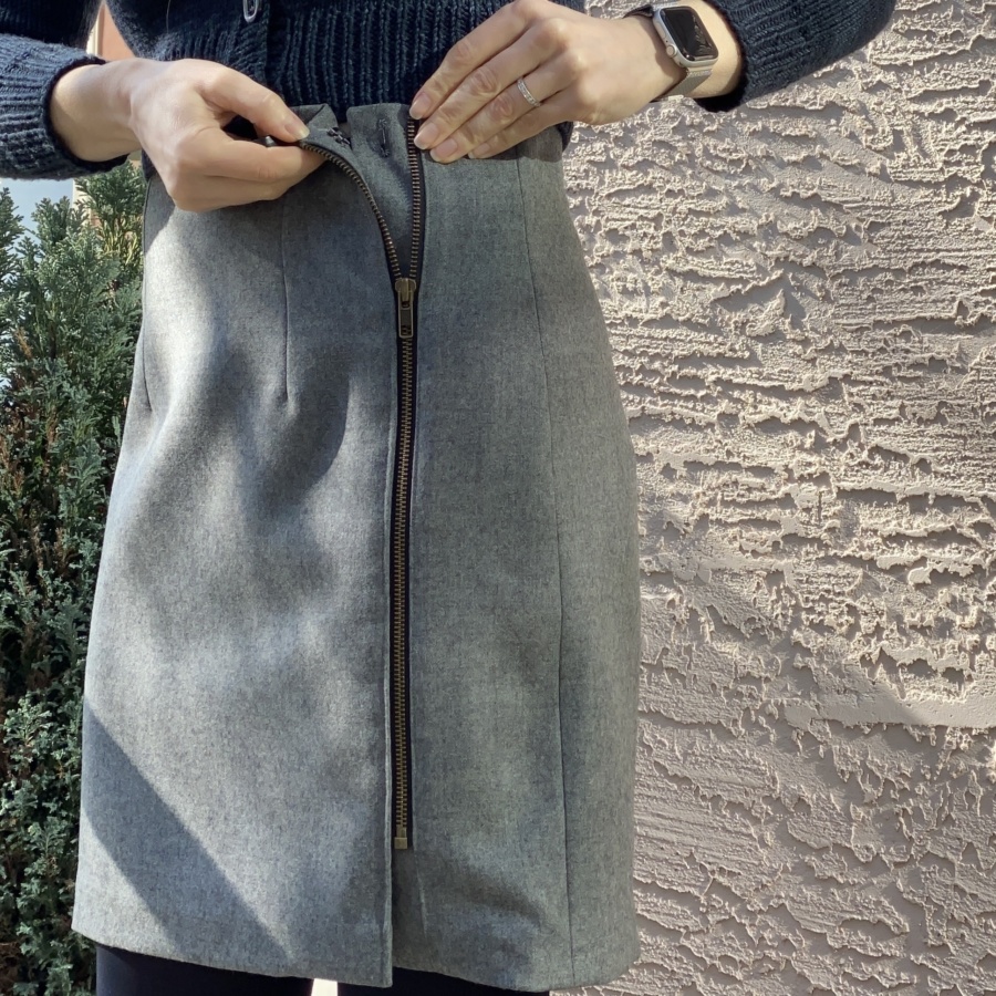 Close up of grey skirt with metal zip showing open top edge with hook and bar clasp