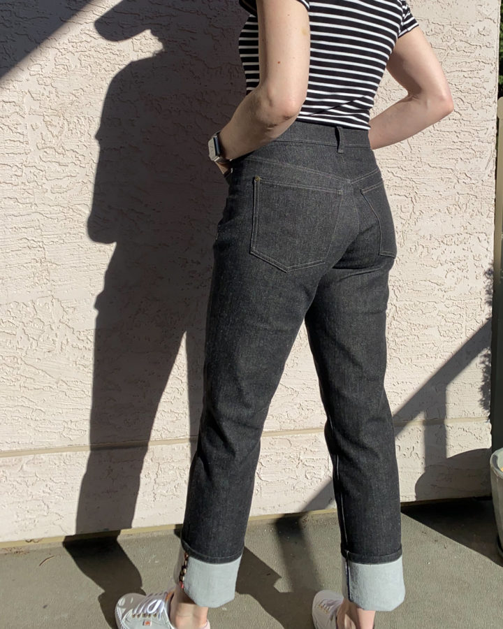 Me wearing my black Brooks Jeans and a black and white striped top. My back is to the camera and my hands are in my front pockets. Photo is cropped at my the upper back.